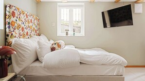 A bedroom with a bed, a window, a TV, and a ceiling with exposed beams. - 500m to Bryggen • Renovated 2025 • Bathtub Bliss! (Bergen)