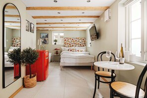 Ein gemütliches Zimmer mit einem Bett, einem kleinen Tisch mit Gläsern, einem roten Schrank und einem Spiegel.