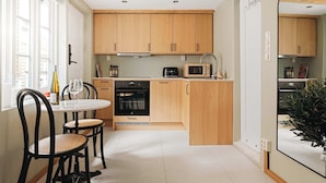 A compact kitchen with wooden cabinets, a dining table with chairs, and a microwave. - 500m to Bryggen • Renovated 2025 • Bathtub Bliss! (Bergen)
