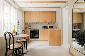Eine kleine Küche mit Holzausbau, einem Esstisch mit Stühlen und einer Mikrowelle.