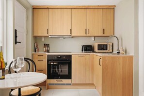 Eine kompakte Küche mit Holzausstattung, Backofen, Mikrowelle und einem Essbereich mit Tisch und Stühlen.