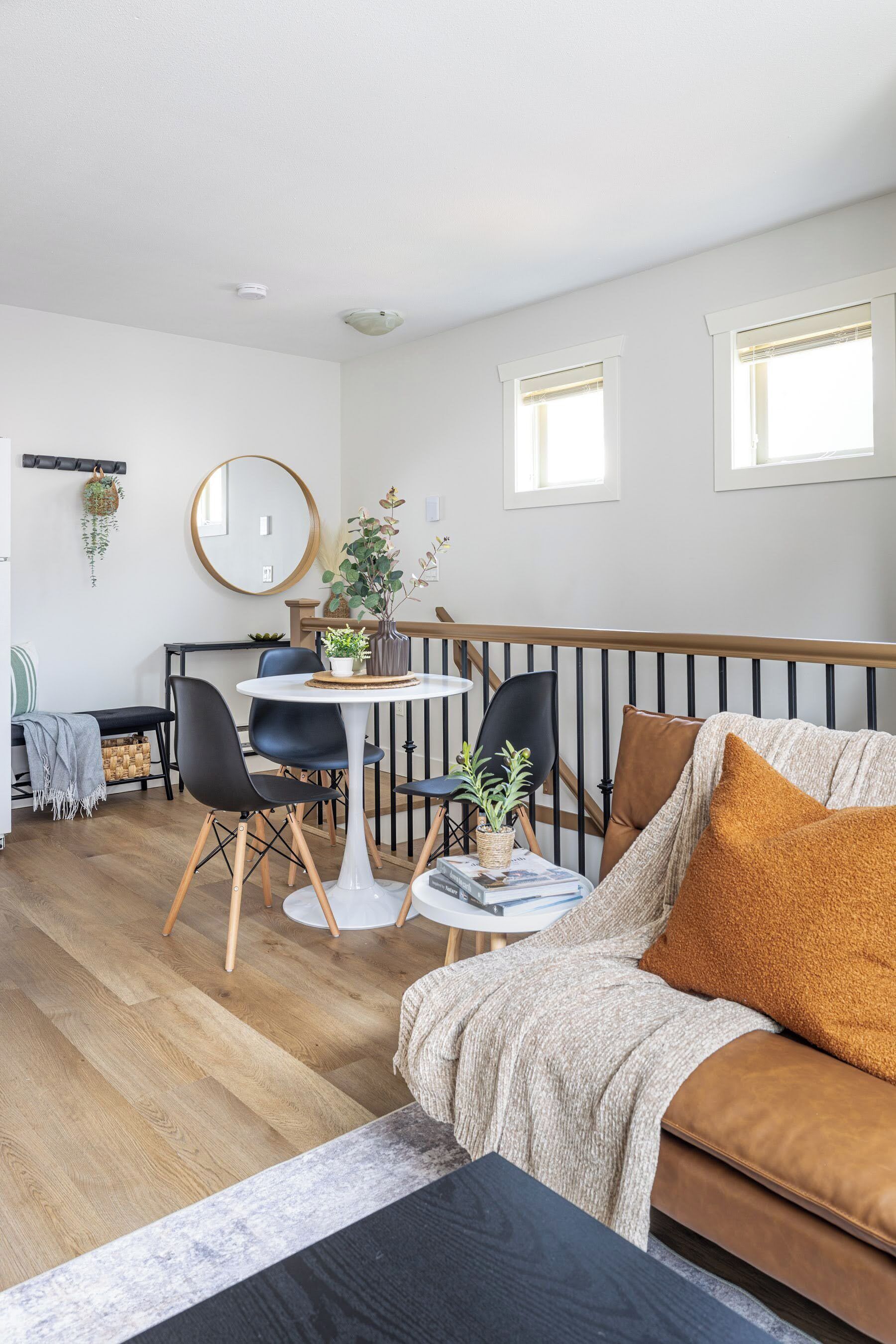 Een moderne woonkamer met een bank, stoelen, een eettafel en een trap.