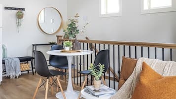 Een moderne woonkamer met een bank, stoelen, een eettafel en een trap.
