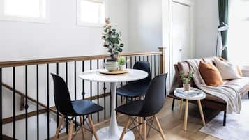 Una sala de estar moderna con comedor, piso de madera y un balcón con barandilla.