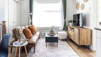 Una sala de estar moderna con sofá, mesa de centro y televisor.