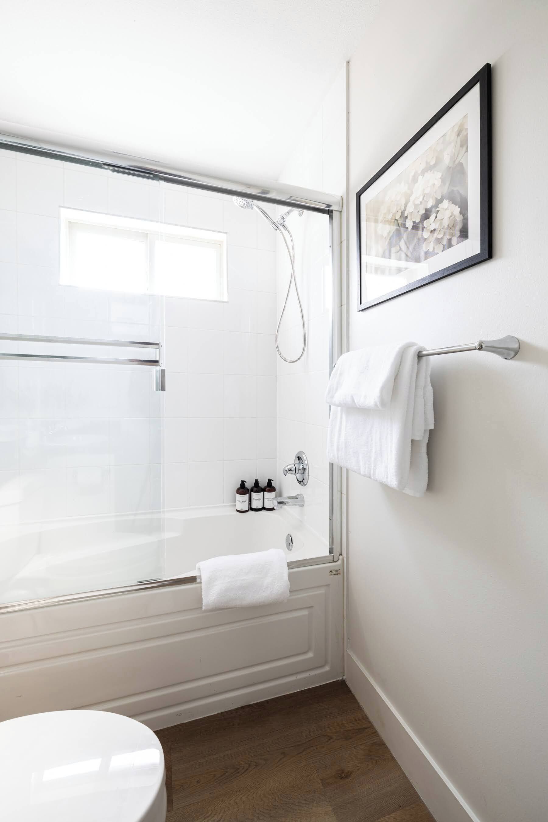 A modern bathroom with a glass-enclosed shower, a white bathtub, and a toilet.