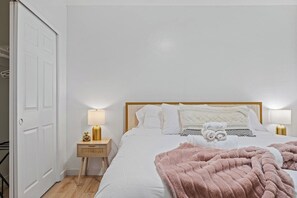 A hotel room with a bed, bedside lamps, a nightstand, and a door.