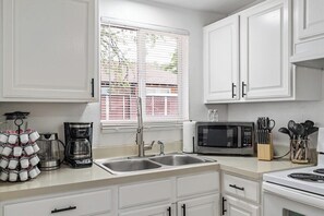 A kitchen with white cabinets, a double sink, a coffee maker, a microwave, and a stove. - 1BR Downtown-Close SLC Home, Sleeps 4 (Salt Lake City)