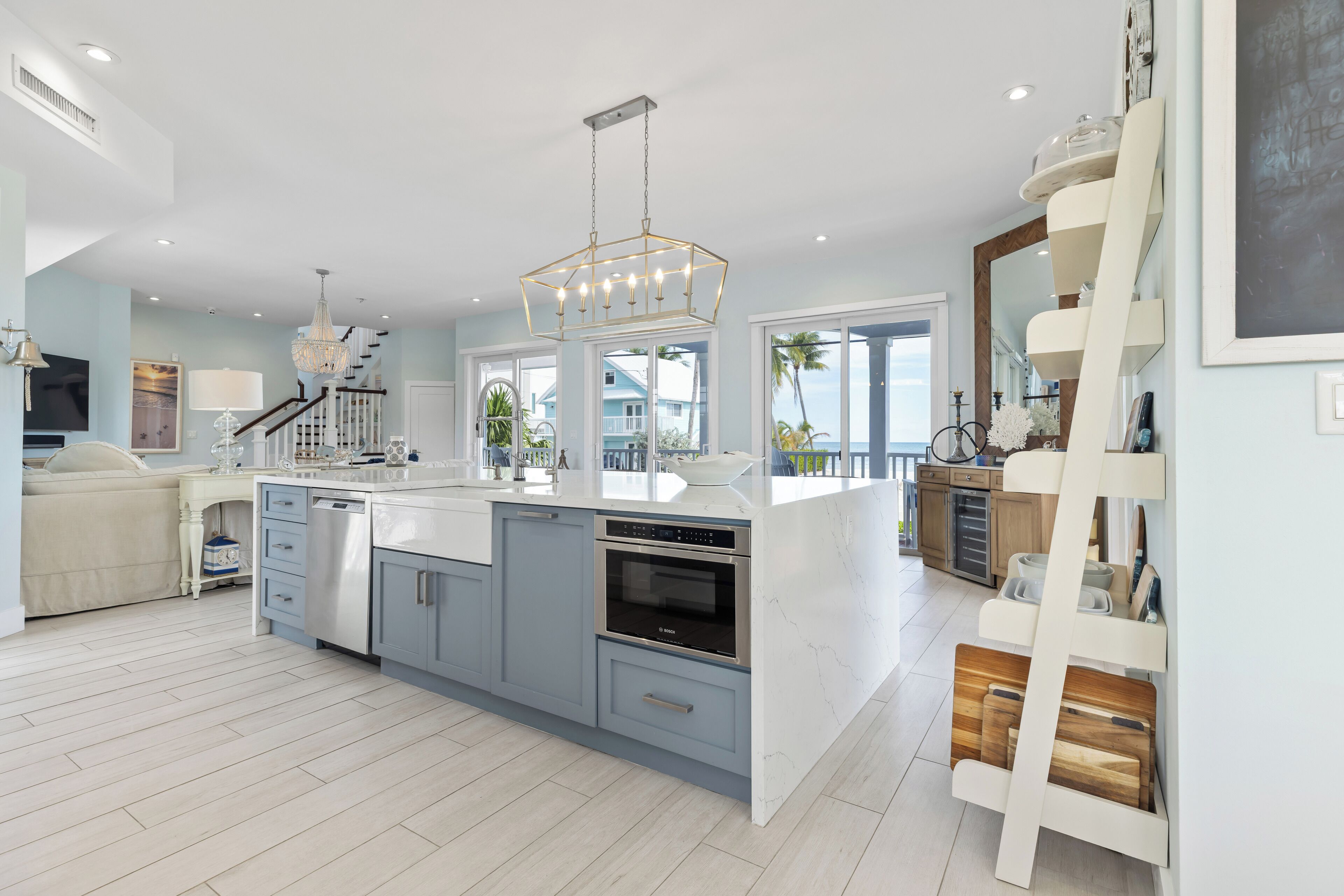A modern kitchen with a central island, built-in appliances, and a view to the outside.