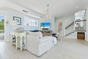 Ein großzügiges Wohnzimmer mit einer breiten Couch, einem Fernseher und einer Treppe, die in eine obere Etage führt.