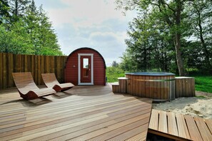 A wooden deck with lounge chairs, a hot tub, and a red building with a door. - Nature retreat with sauna in Ho (Blåvand)