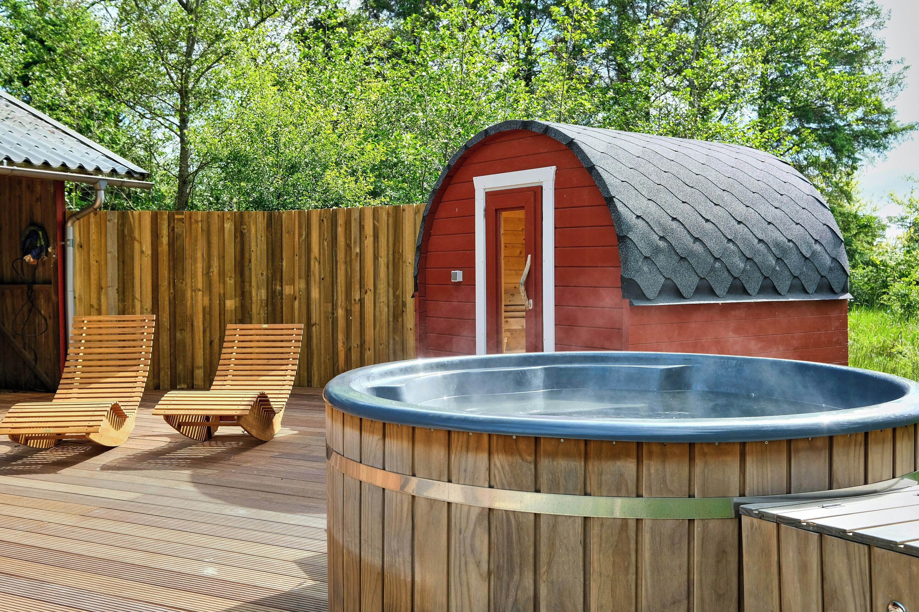 A wooden deck with two lounge chairs and a hot tub.