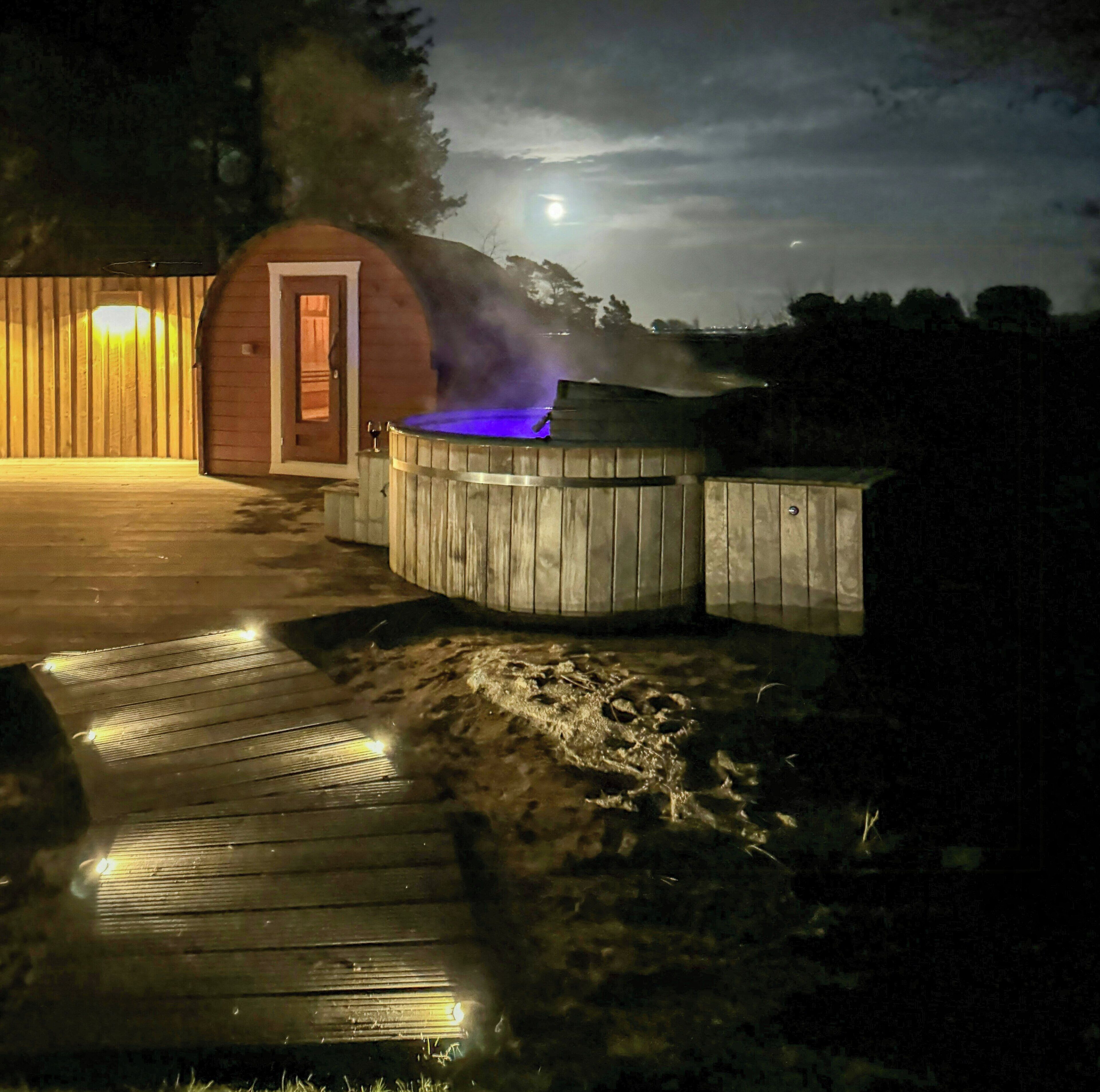Een jacuzzi met een houten terras en een houten constructie op de achtergrond.