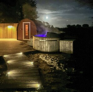 Een jacuzzi met een houten terras en een houten constructie op de achtergrond.