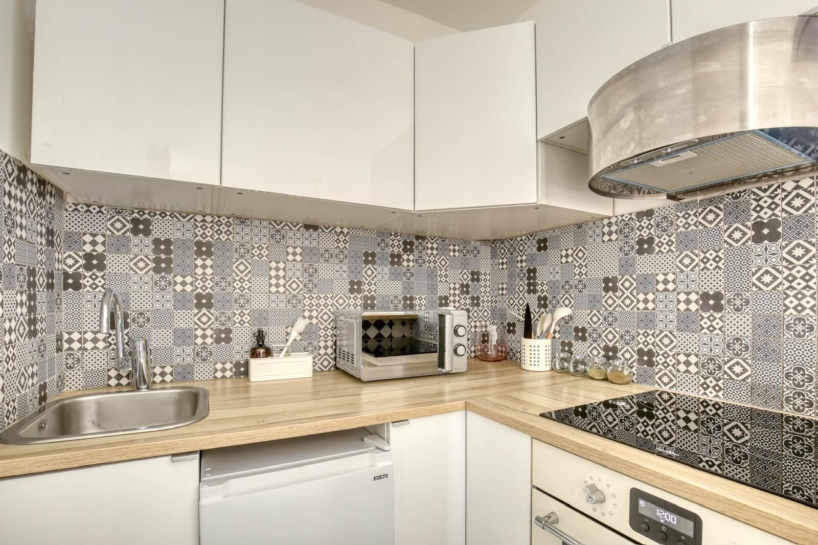 A kitchen with patterned backsplash, stainless steel appliances, and a built-in dishwasher.