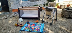 Un corralito para bebé con techo de malla, un asiento infantil y un tapete de juegos con personajes de dibujos animados.