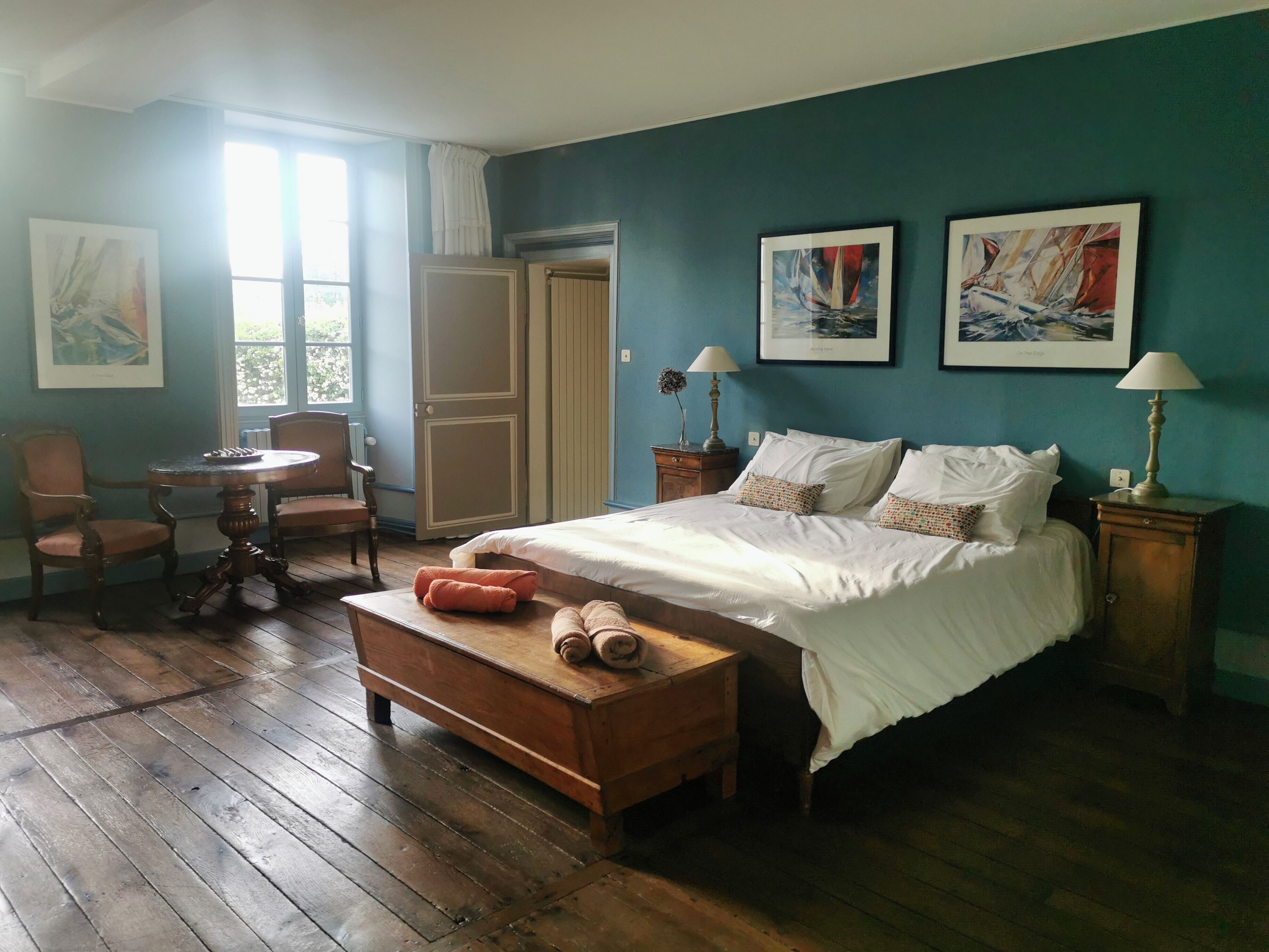 Ein Schlafzimmer mit einem Bett, einem Holztisch, einem Stuhl und zwei Bildern an der Wand.