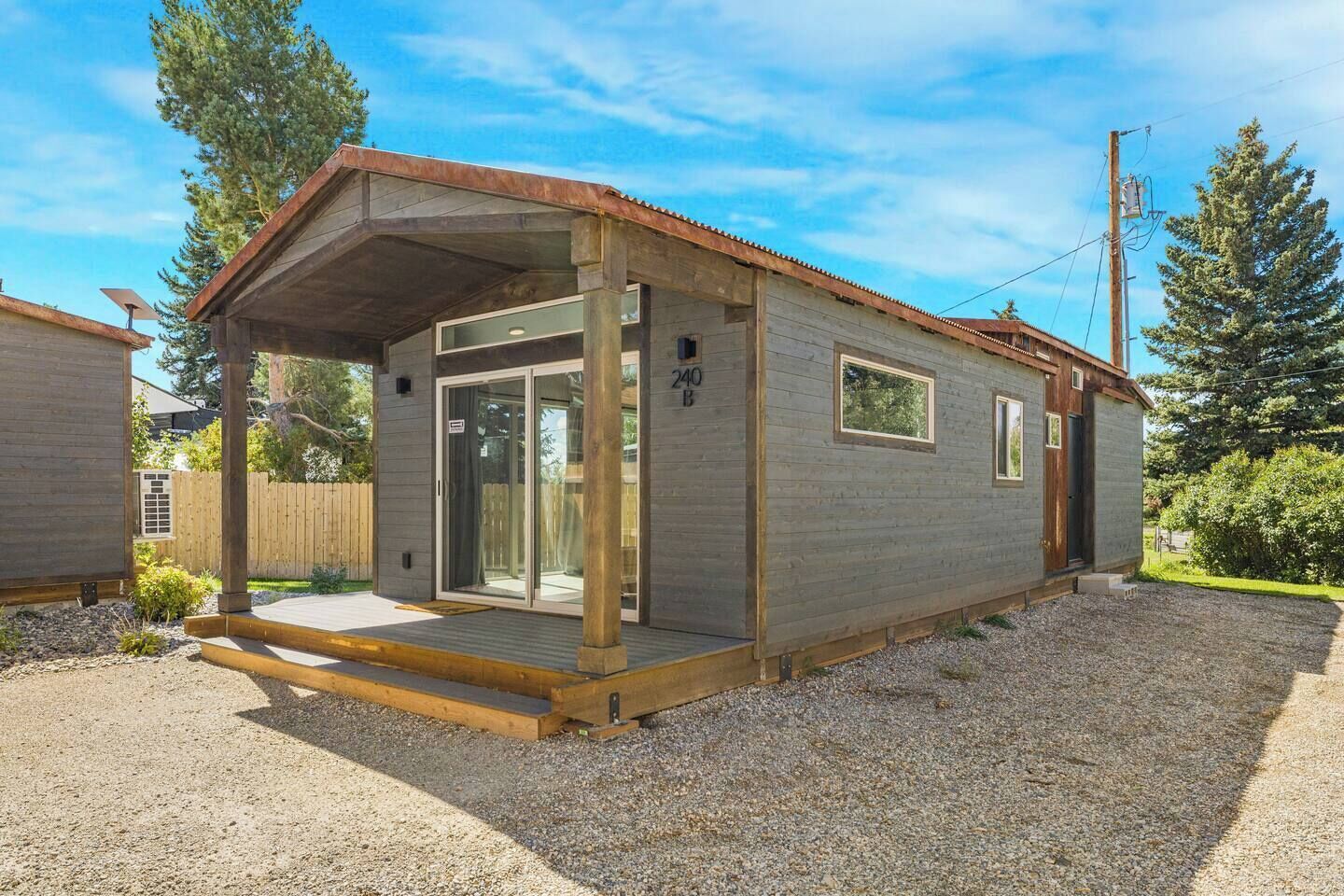 A single-story wooden cabin with a covered porch, a sliding glass door, and a small window.