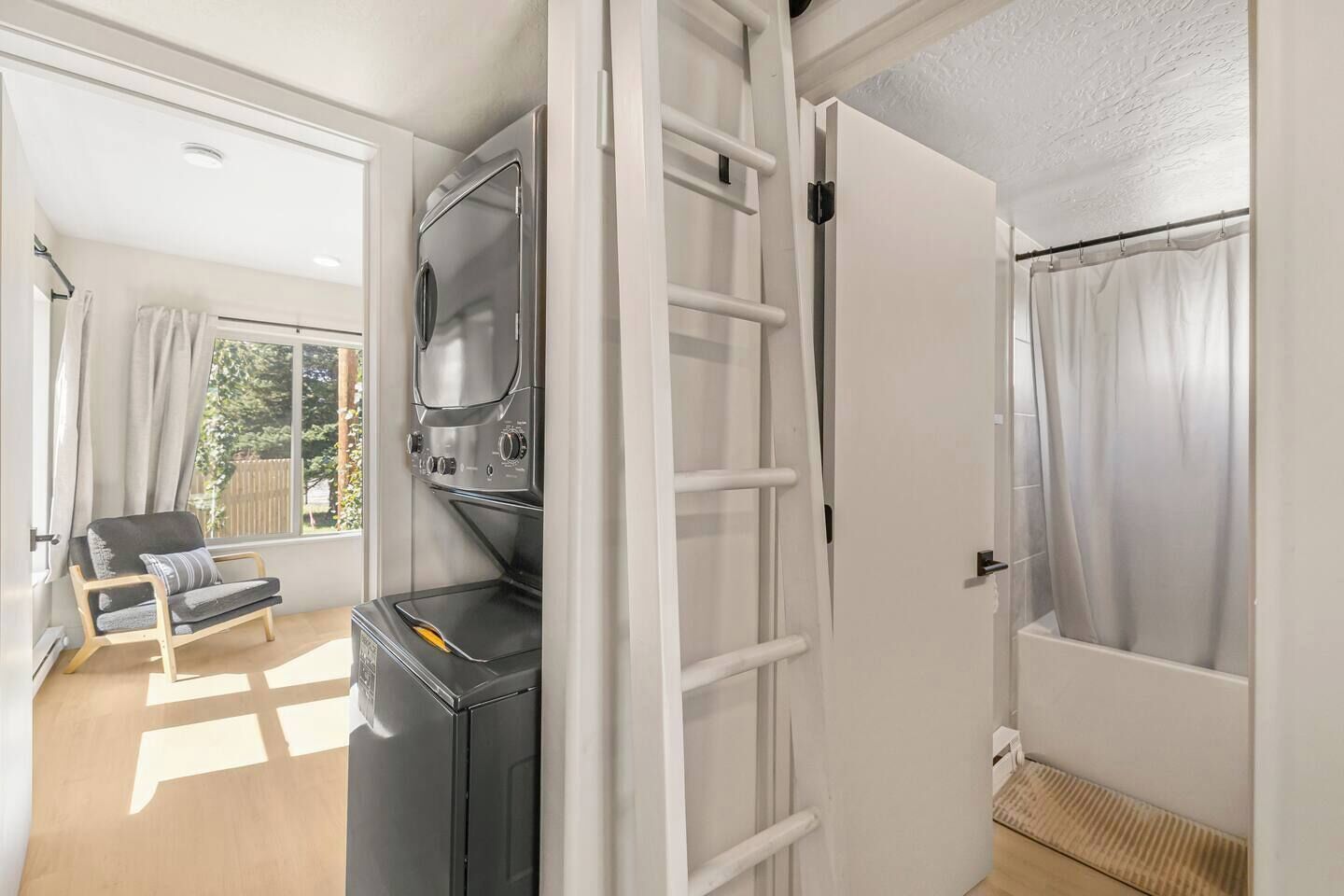 A compact living space with a kitchenette, a seating area with a sofa, and a door leading to a bathroom with a shower.