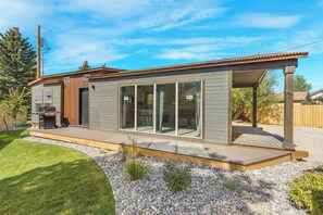 Ein modernes Haus mit Terrasse, Grill und einer großen Schiebetür.