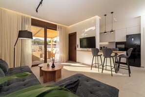 A modern living room with a sofa, a coffee table, and a dining area with chairs. - Irisma Luxury Villa I | Private Pool near Heraklion, Crete (Archanes)