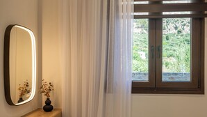 Huoneessa on puinen työpöytä, kannettava tietokone, peili ja ikkuna, jossa on verhot.
