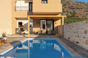A modern building with a pool, outdoor seating, and a stone wall. - Irisma Luxury Villa I | Private Pool near Heraklion, Crete (Archanes)