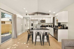 A modern kitchen with a central island, bar stools, and a dining area.