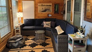 A cozy room with a curved dark blue sofa, a small round table, a lamp, and a patterned rug.