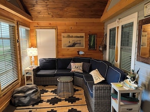 A cozy room with a curved dark blue sofa, a small round table, a lamp, and a patterned rug.