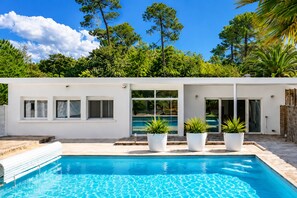 Ein modernes Haus mit Swimmingpool, weißen Außenwänden und großen Fenstern.