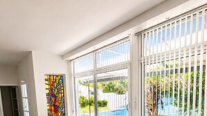 A modern living room with a sectional sofa, a coffee table, and a view of a swimming pool through large windows. - EXCEPTIONAL VILLA IN SAINT-PALAIS-SUR-MER - HEATED POOL - 5 BEDROOMS (Saint-Palais-sur-Mer)