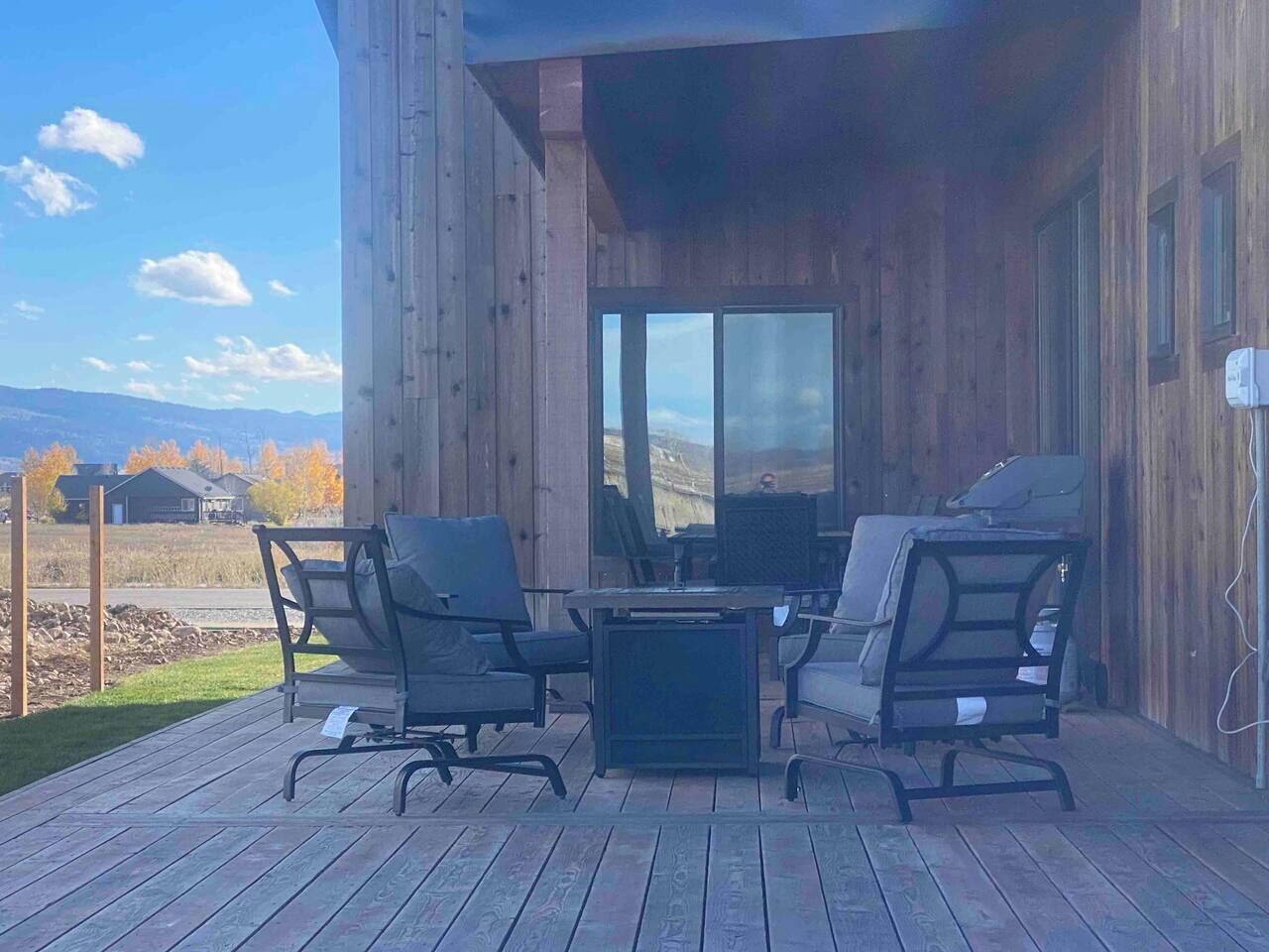 Una terrazza esterna con pavimento in legno, un tavolo e quattro sedie.