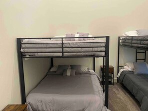 Een slaapkamer met een enkel bed en twee stapelbedden.