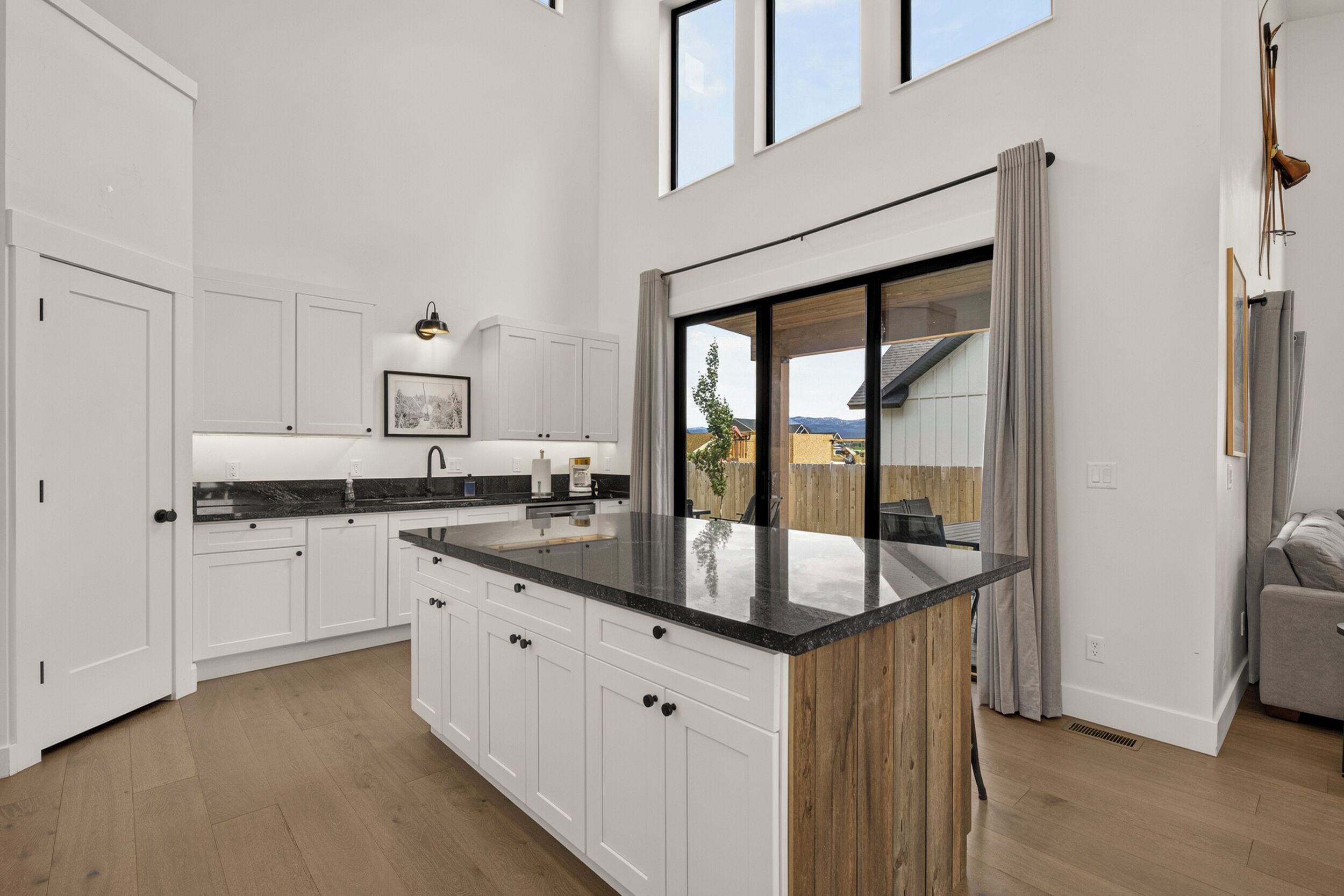 A modern kitchen with white cabinetry, a black countertop, and a large island.