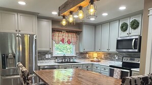 Una cucina moderna con isola centrale, elettrodomestici in acciaio inossidabile e illuminazione a sospensione.