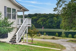 Ein Haus mit Veranda, Treppe und Blick auf einen See mit Bäumen.