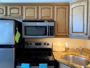 A kitchen with a refrigerator, microwave, stove, and sink. - 2BR/2BA Beach Condo- Full Kitchen-sleeps 4 (Daytona Beach)