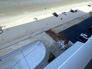 A parking area adjacent to a beach with several cars and a few people walking. - 2BR/2BA Beach Condo- Full Kitchen-sleeps 4 (Daytona Beach)