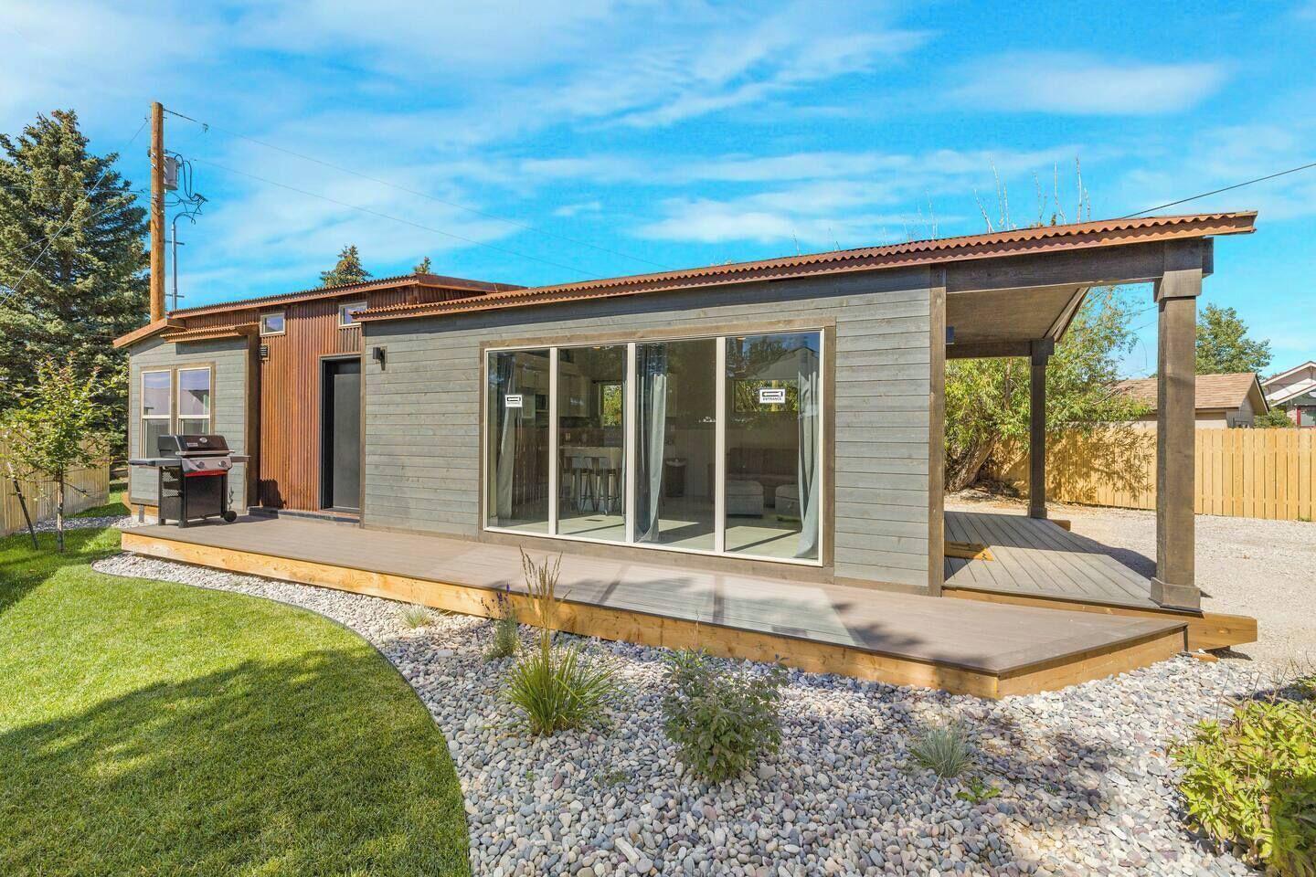 Una casa moderna con un patio, una barbacoa y un amplio ventanal corredera.