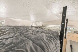 Un dormitorio pequeño con cama, escritorio y ventana.