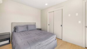 Quarto com cama, mesas de cabeceira, guarda-roupa e luz no teto.