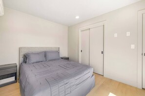 Ein Schlafzimmer mit Bett, Nachttischen, einem Kleiderschrank und einer Deckenleuchte.