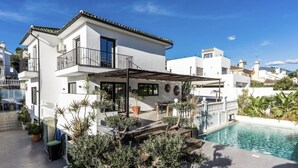 Uma casa moderna de dois andares com piscina, área de estar externa e varanda coberta.