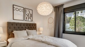 Quarto com cabeceira estofada, luminária redonda grande, um sonho capturado e janela com cortinas.