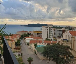 Uma área residencial costeira com piscina, edifícios com telhados vermelhos e vista para o mar.