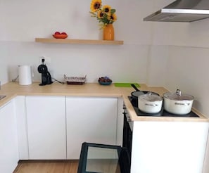 Uma cozinha com armários brancos, bancada, fogão e pia.