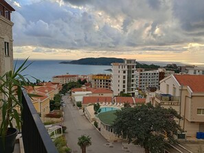 A coastal residential area with a view of the sea, a swimming pool, and various buildings. - Cozy 1-bedroom apartment in lovely Budva with sea view. (Budva)