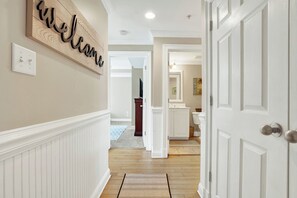 Um corredor com uma placa de boas-vindas, um interruptor de luz e uma porta para o banheiro.
