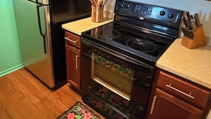 Eine Küche mit Holzausstattung, einem Edelstahlkühlschrank, einer Mikrowelle, einem Backofen und einer Arbeitsplatte mit Messerblock.